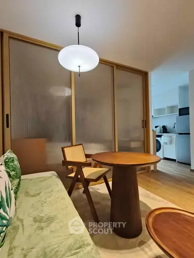 Chic living room with modern furniture and sliding doors, adjacent to a sleek kitchen area.