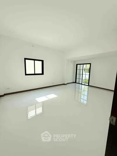 Spacious bright room with glossy white tiles and large window for natural light.