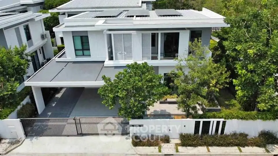 Modern two-story house with sleek design and lush greenery, featuring a spacious driveway and contemporary architecture.