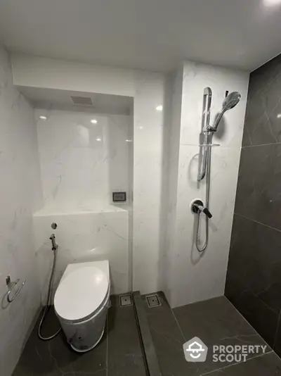 Modern bathroom with sleek design, featuring a wall-mounted toilet and a stylish shower area with marble accents.