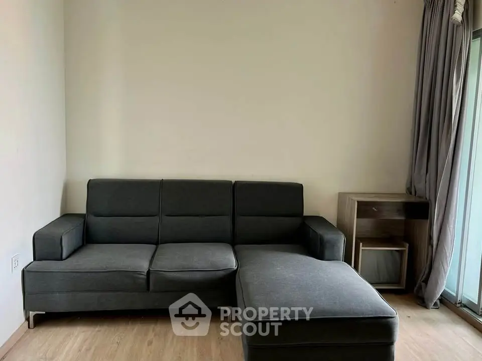 Modern living room with sleek gray sectional sofa and wooden flooring, perfect for cozy relaxation.