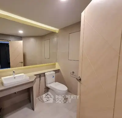 Modern bathroom with sleek fixtures and large mirror in a contemporary home.