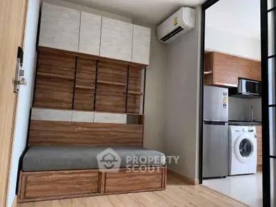 Modern studio apartment with built-in wooden furniture and compact kitchen appliances.