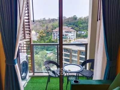 Charming balcony with lush view and cozy seating area in modern apartment.