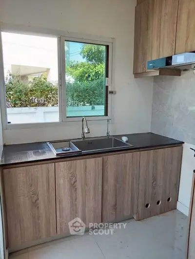 Modern kitchen with wooden cabinets and large window for natural light.