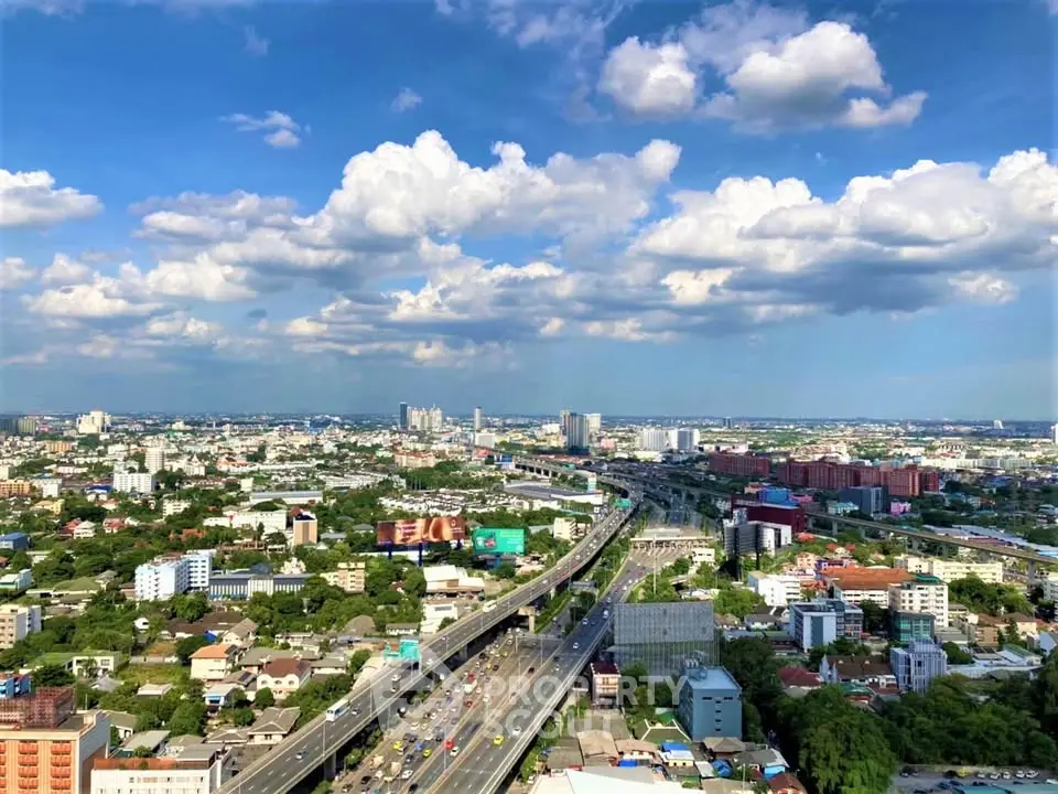 Stunning aerial view of urban landscape with highway and city skyline under a vibrant blue sky.