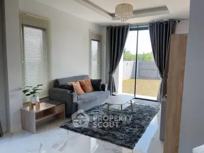 Modern living room with elegant decor and large windows offering natural light and garden view.