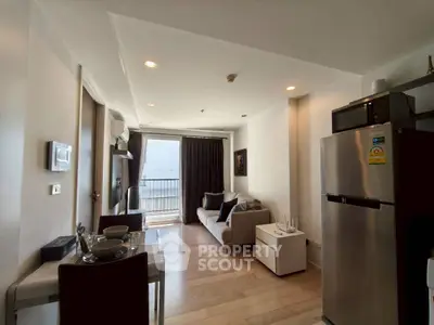Modern living room with balcony view, sleek furniture, and stainless steel appliances in a cozy apartment.