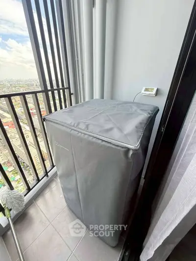 Compact balcony with city view and covered appliance, ideal for urban living.