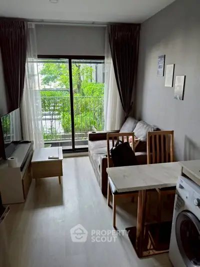 Cozy living room with natural light, modern furniture, and a washing machine near a large window.