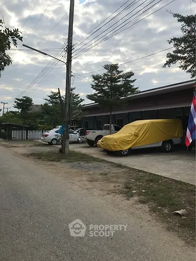 Charming suburban street view with parked cars and lush greenery, ideal for peaceful living.