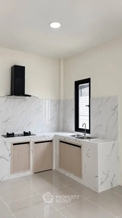 Modern kitchen with marble countertops and gas stove in a sleek open layout design.