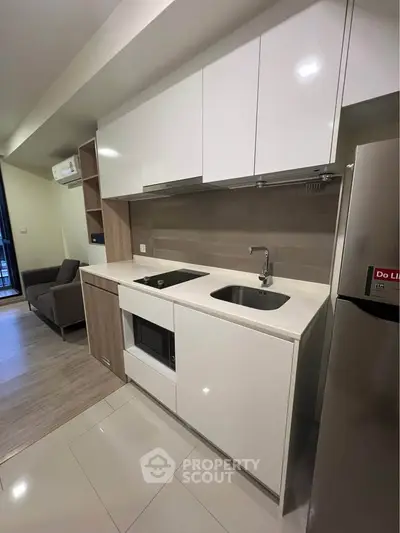 Modern kitchen with sleek white cabinets and integrated appliances in a stylish apartment.