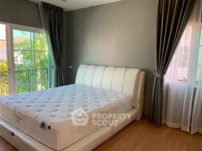 Spacious bedroom with elegant decor and large windows offering natural light.