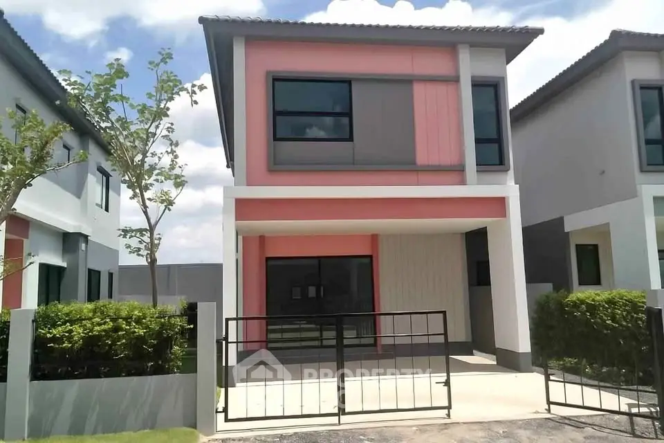 Modern two-story house with vibrant facade and gated entrance in suburban setting.