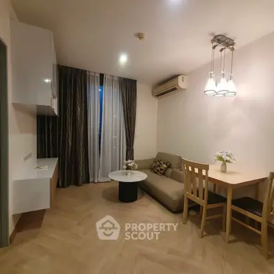 Cozy living room with modern decor and dining area, featuring elegant lighting and wooden flooring.