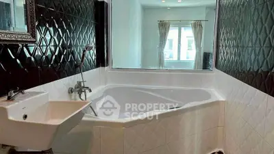 Luxurious bathroom with unique corner bathtub and elegant black tile design.