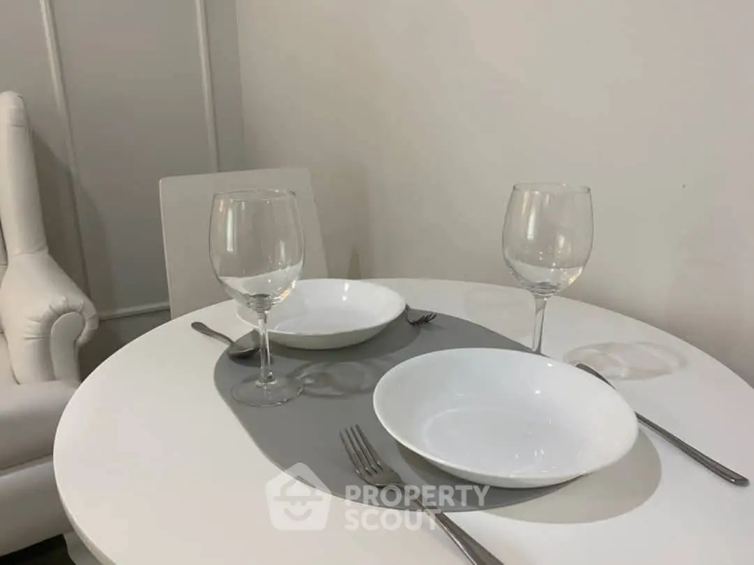 Elegant dining setup with white tableware and wine glasses in a modern interior.