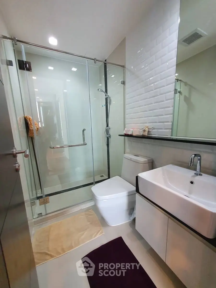 Modern bathroom with glass shower, sleek sink, and contemporary design.