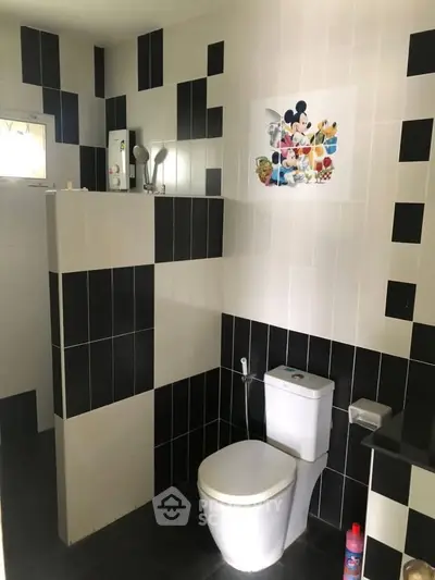 Modern bathroom with black and white tiles featuring a toilet and decorative wall art.