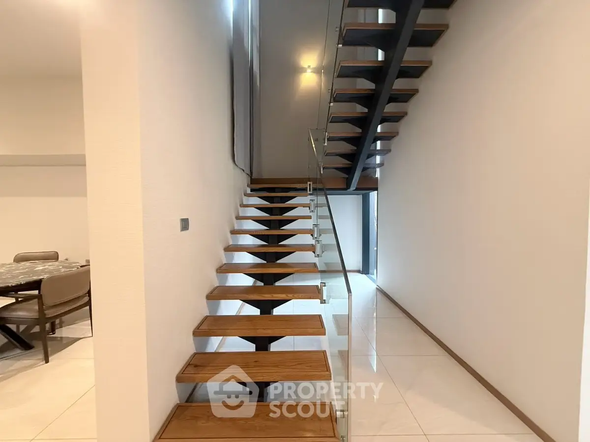 Modern staircase with wooden steps and glass railing in a stylish home interior