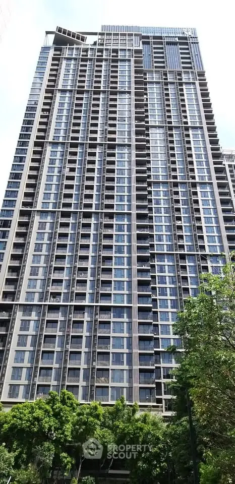 Stunning high-rise building with modern architecture and lush greenery at the base, perfect for urban living.