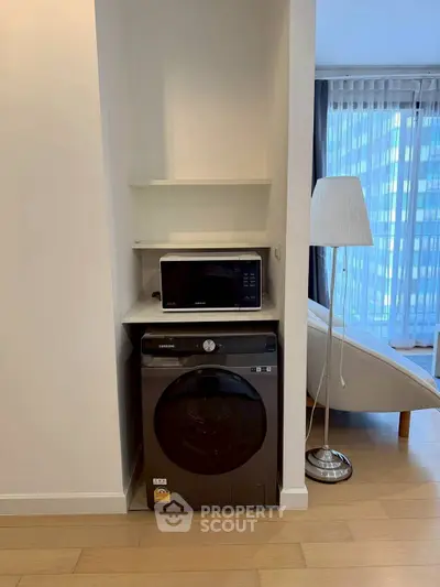 Modern apartment interior with washing machine and microwave in a cozy living space.