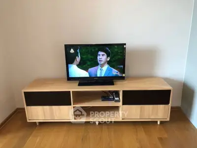 Modern living room with sleek wooden TV stand and flat-screen television.