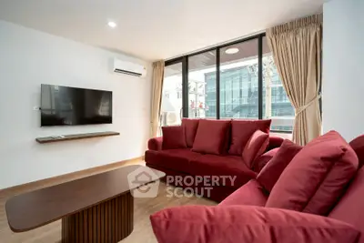 Modern living room with red sofas and large windows in a stylish apartment.