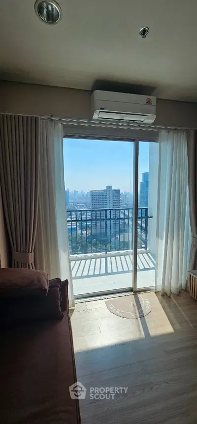 Modern living room with balcony and city view, featuring floor-to-ceiling windows and air conditioning.