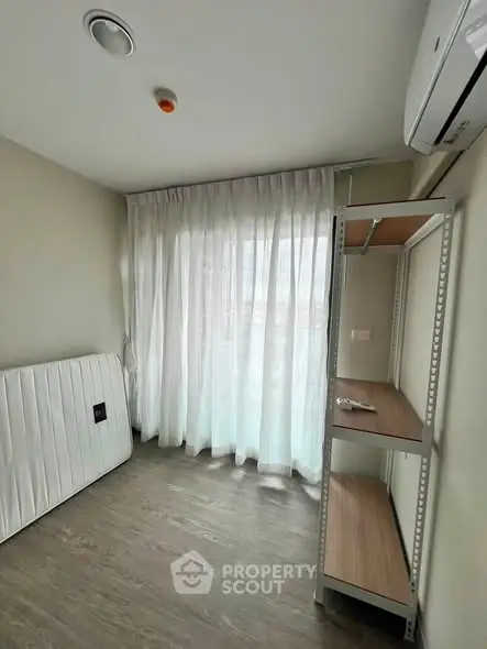 Spacious room with large window and shelving unit, perfect for versatile use.