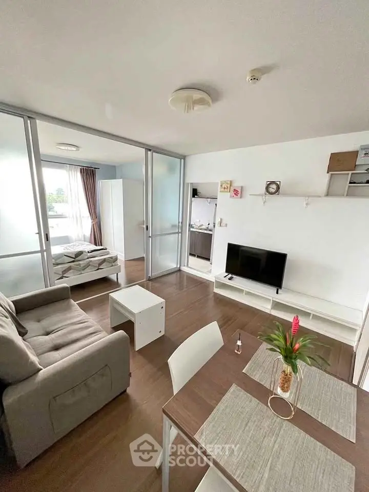 Modern living room with cozy sofa, TV, and dining area in open-plan apartment.