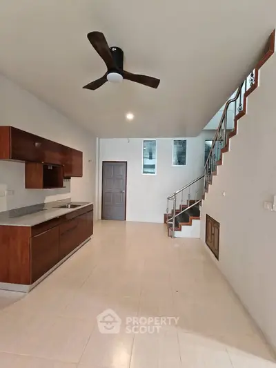 Spacious modern kitchen with sleek cabinetry and elegant staircase in open layout home.