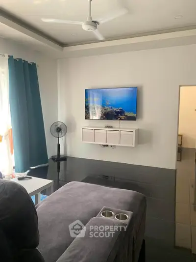 Modern living room with sleek black flooring, wall-mounted TV, and cozy seating area.
