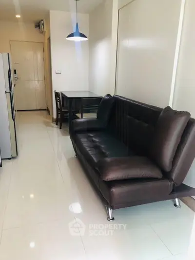 Modern apartment interior with sleek leather sofa and dining area, showcasing minimalist design and bright lighting.