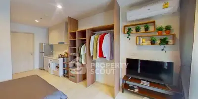 Modern studio apartment with open wardrobe, compact kitchen, and cozy living area.