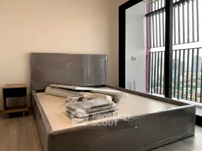 Modern bedroom with large windows and city view, featuring a new bed frame and nightstand.