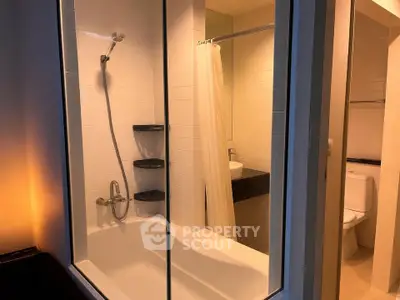 Modern bathroom with glass-enclosed bathtub and sleek fixtures