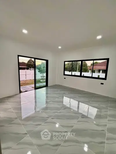 Spacious modern living room with large windows and glossy tiled floor, offering a bright and airy ambiance.