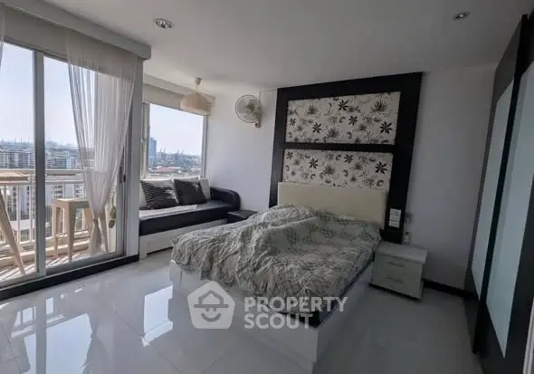 Modern bedroom with balcony and city view, featuring stylish decor and natural light.