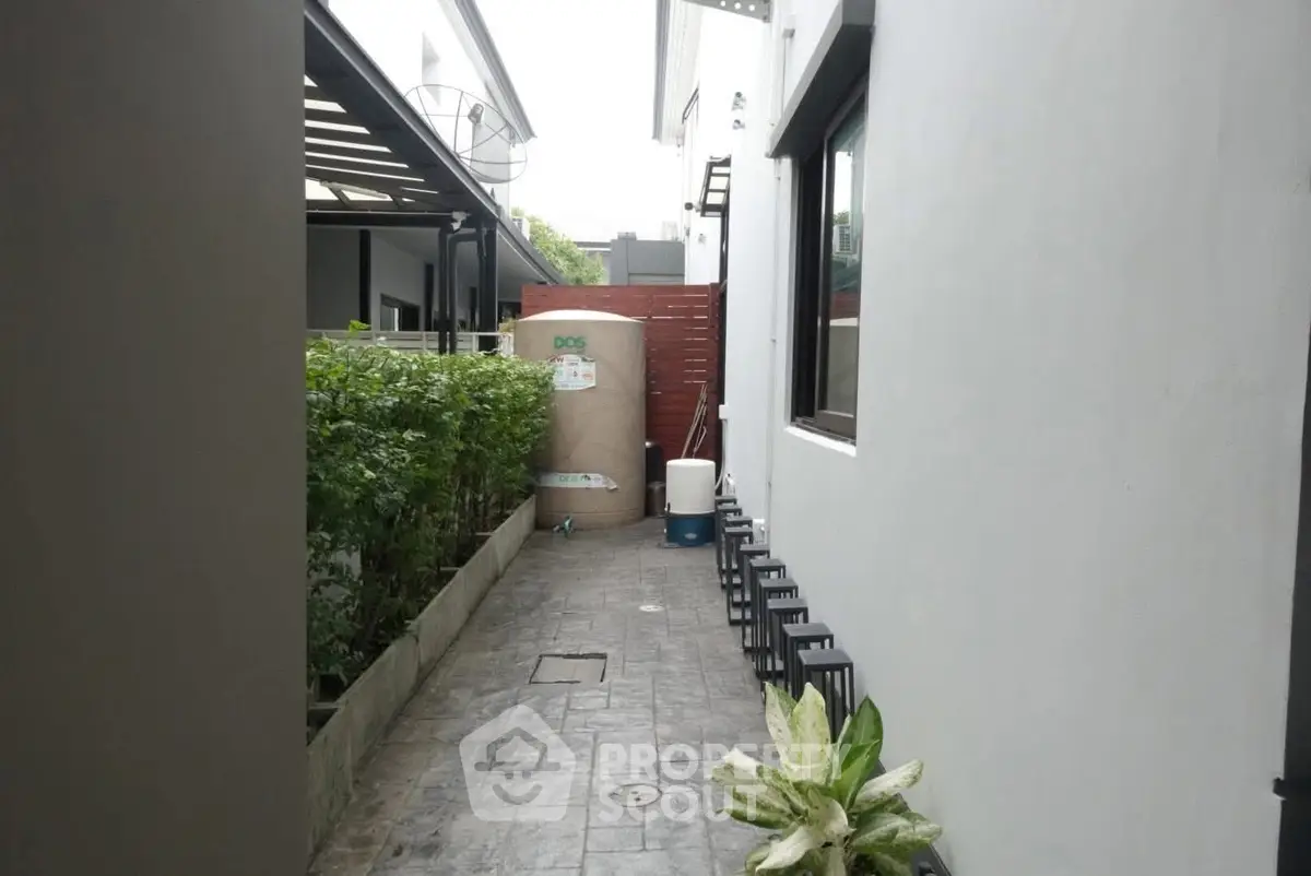 Modern exterior walkway with garden and utility area in contemporary home.