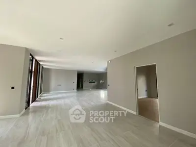 Spacious open-plan living area with modern tiled flooring and ample natural light.