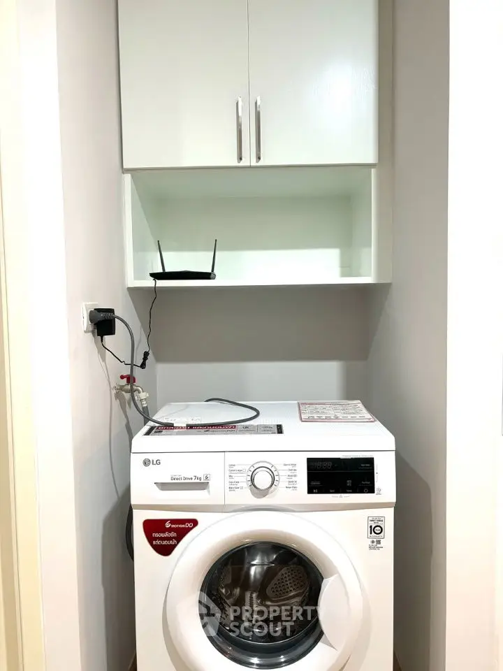 Compact laundry area with modern washing machine and storage cabinet.