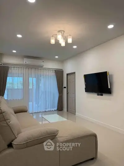 Modern living room with cozy beige sofa, wall-mounted TV, and elegant lighting, perfect for relaxation.