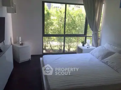 Bright and airy bedroom with large window and modern furnishings, perfect for relaxation.