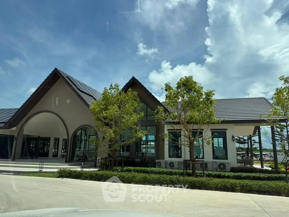 Stunning modern building with lush landscaping and clear blue sky, perfect for real estate investment.
