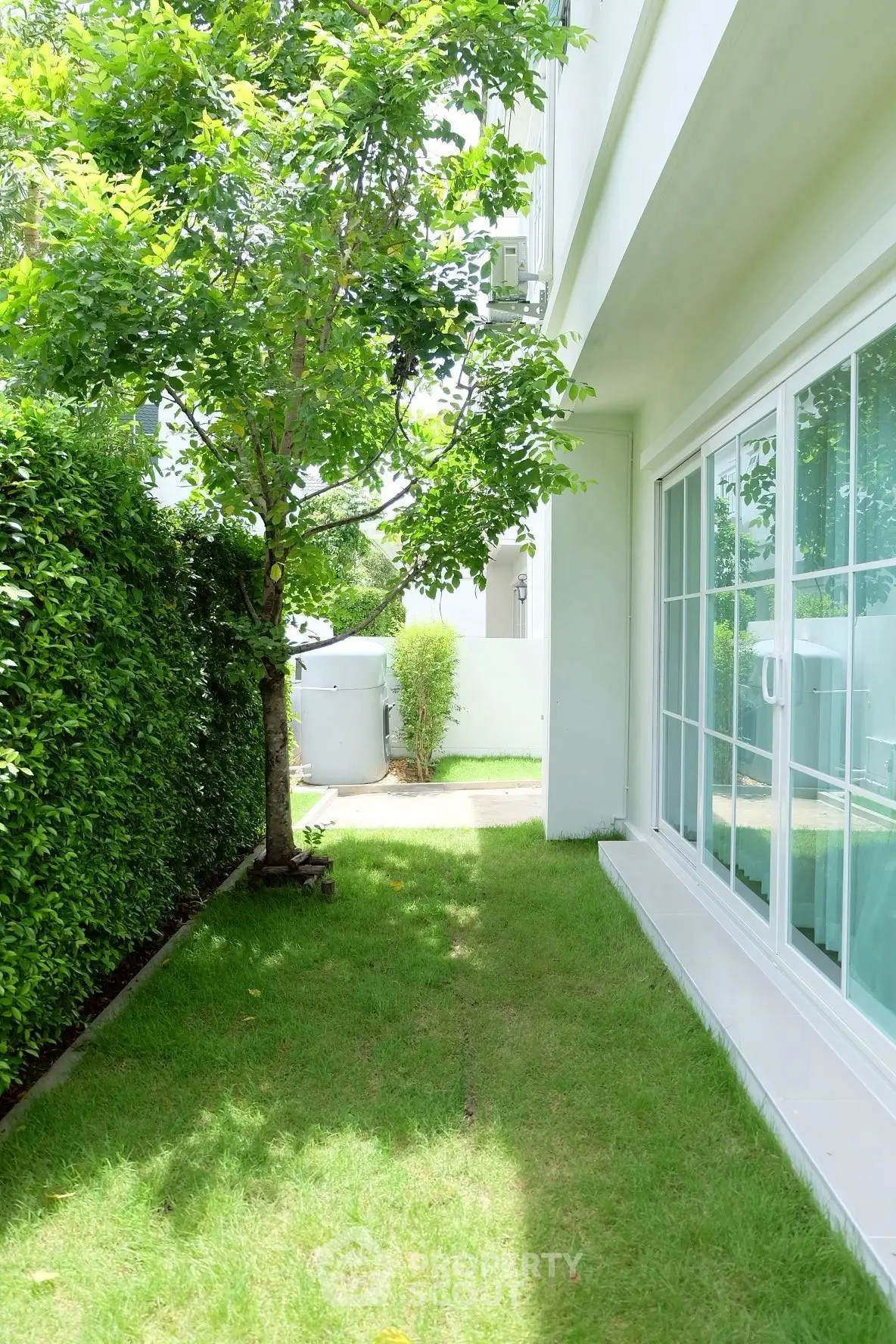 Charming garden view with lush greenery and modern glass doors, perfect for relaxation and outdoor enjoyment.