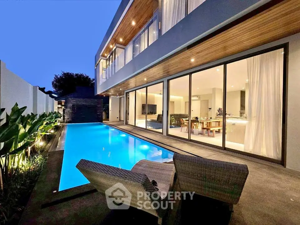 Luxurious modern villa with stunning poolside view and elegant outdoor seating area.