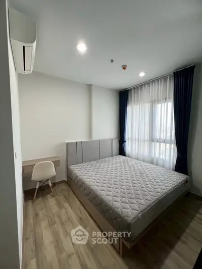 Modern bedroom with large window and stylish decor in a contemporary apartment.