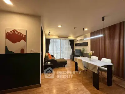 Modern living room with stylish decor and dining area, featuring wood flooring and ambient lighting.